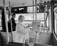 851203 Afbeelding van een dame die gebruik maakt van de nieuwe stempelautomaat in een stadsbus van het Gemeentelijke ...